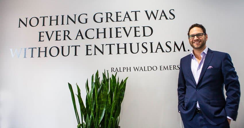 Lee Grunberg, Integracare's President and CEO, standing in front of the quotation painted on the office wall