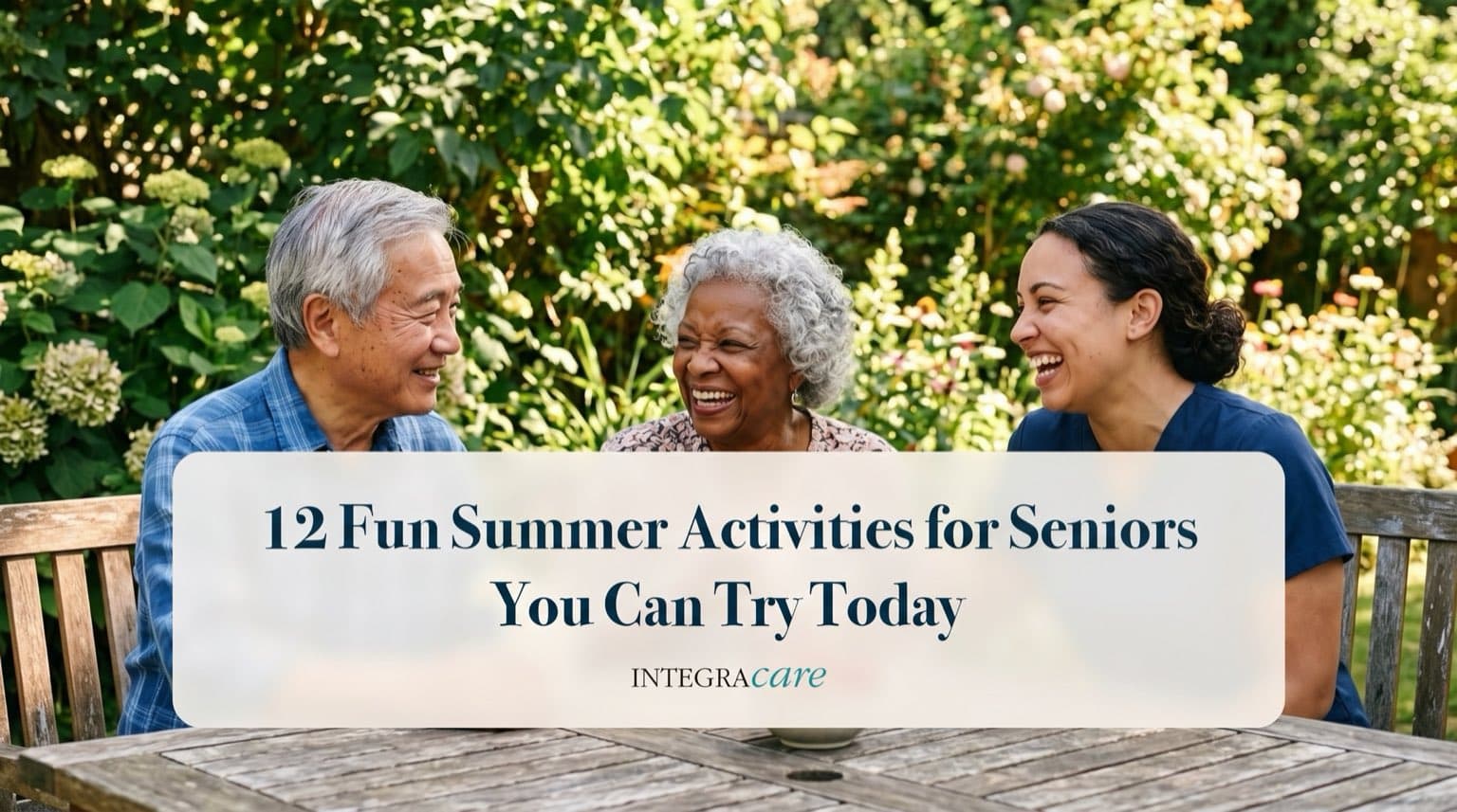 Two seniors and a caregiver laughing together at a wooden table in a lush summer garden