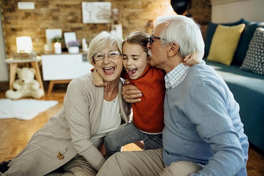Cheerful grandparents and granddaughter having fun together at home