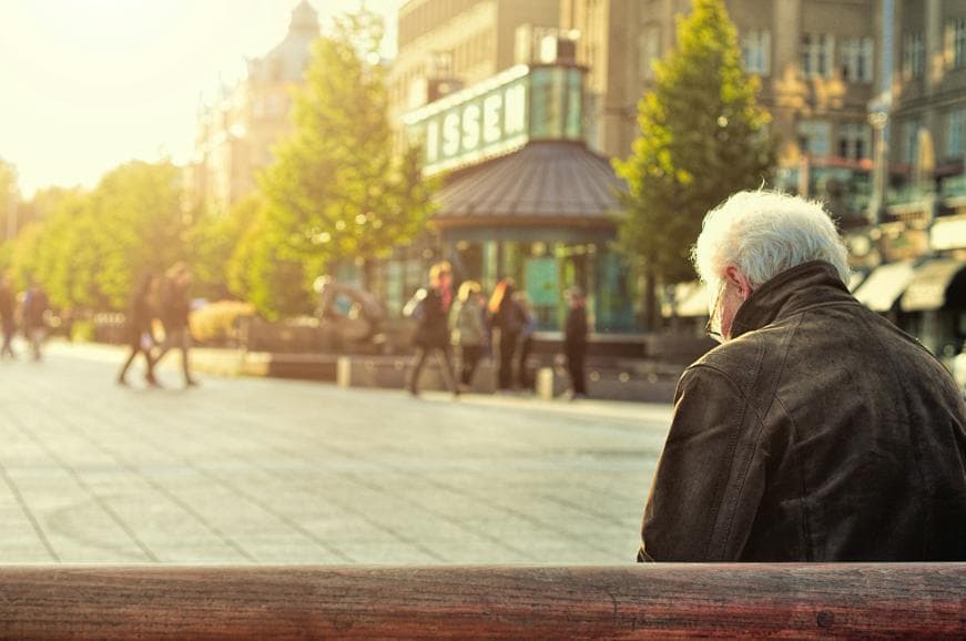 Elderly man sitting on brown wooden bench