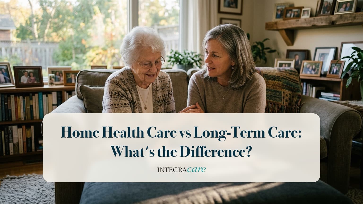An adult daughter sits close to her elderly mother on a sofa in a living room filled with framed family photos, under the title Home Health Care vs Long-Term Care: What's the Difference?