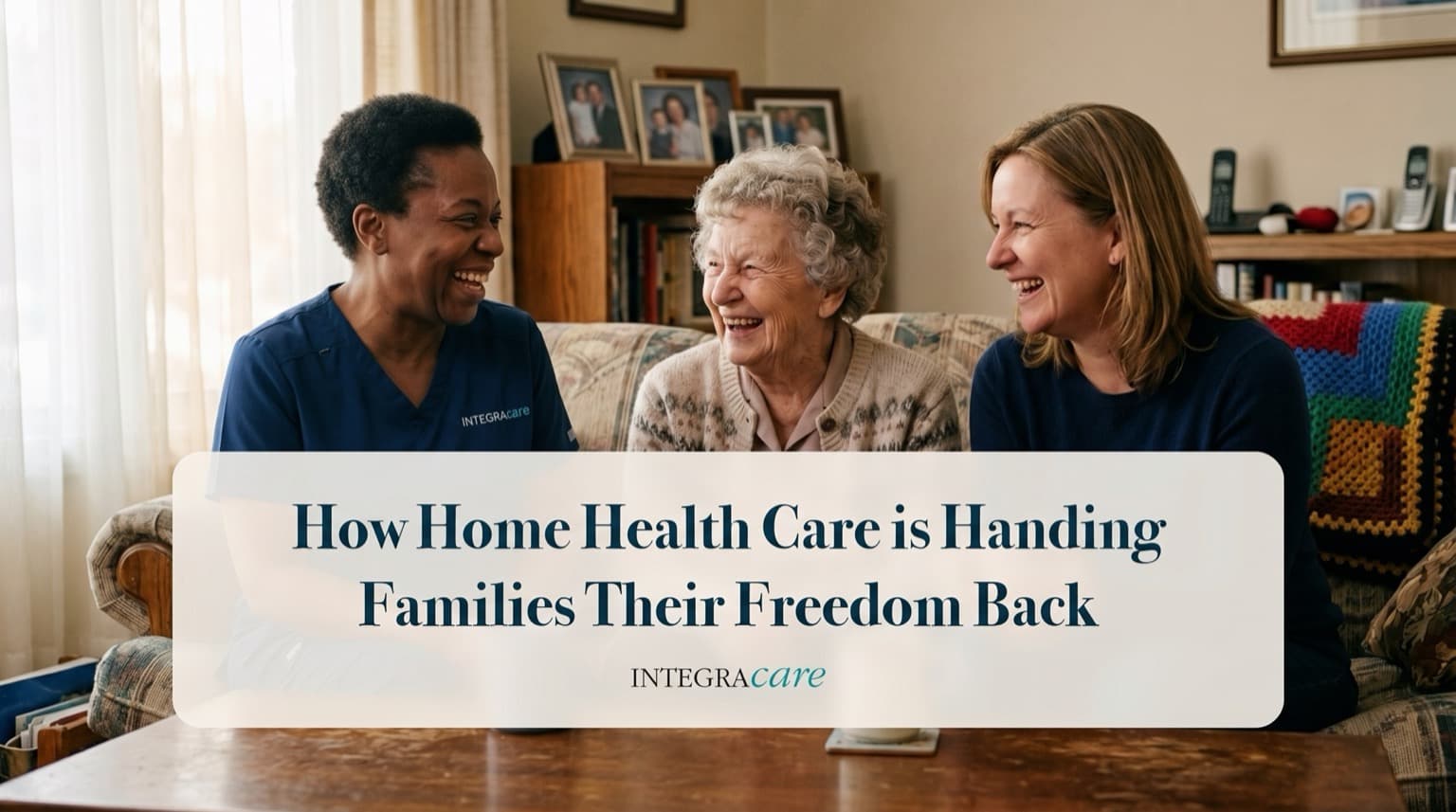Caregiver sharing a laugh with a senior woman and her adult daughter on the living room sofa