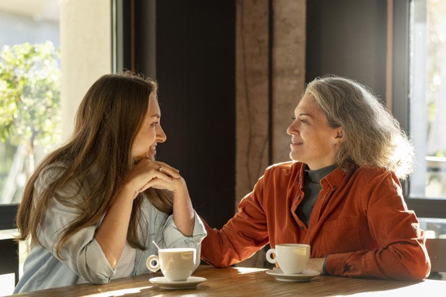 Medium shot smiling mother and daughter sitting at a table