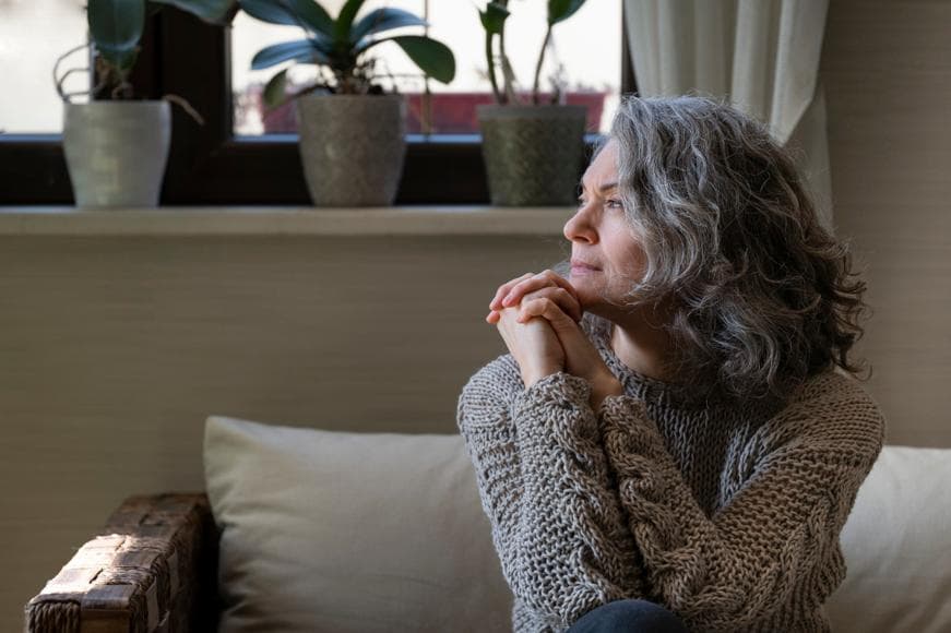 Sad senior woman sitting on a sofa