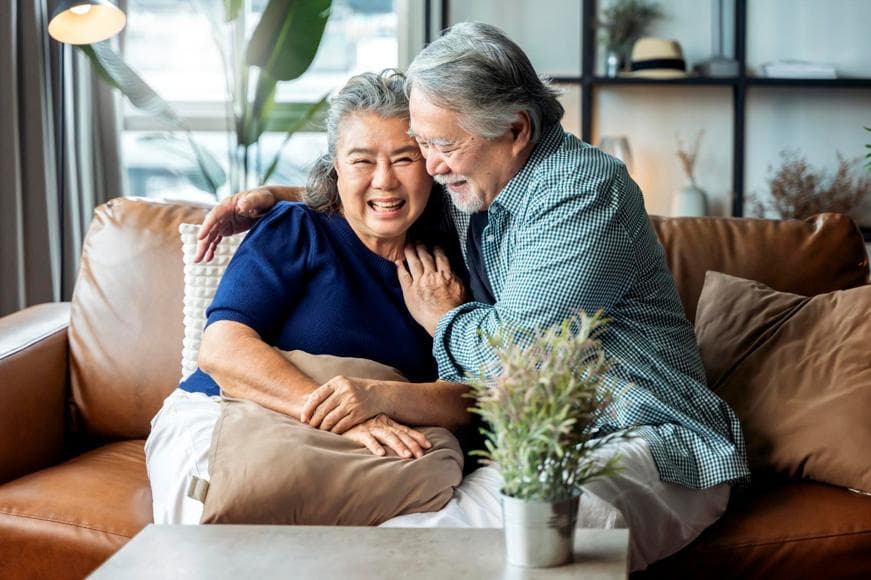 Senior couple sitting together on a sofa smiling