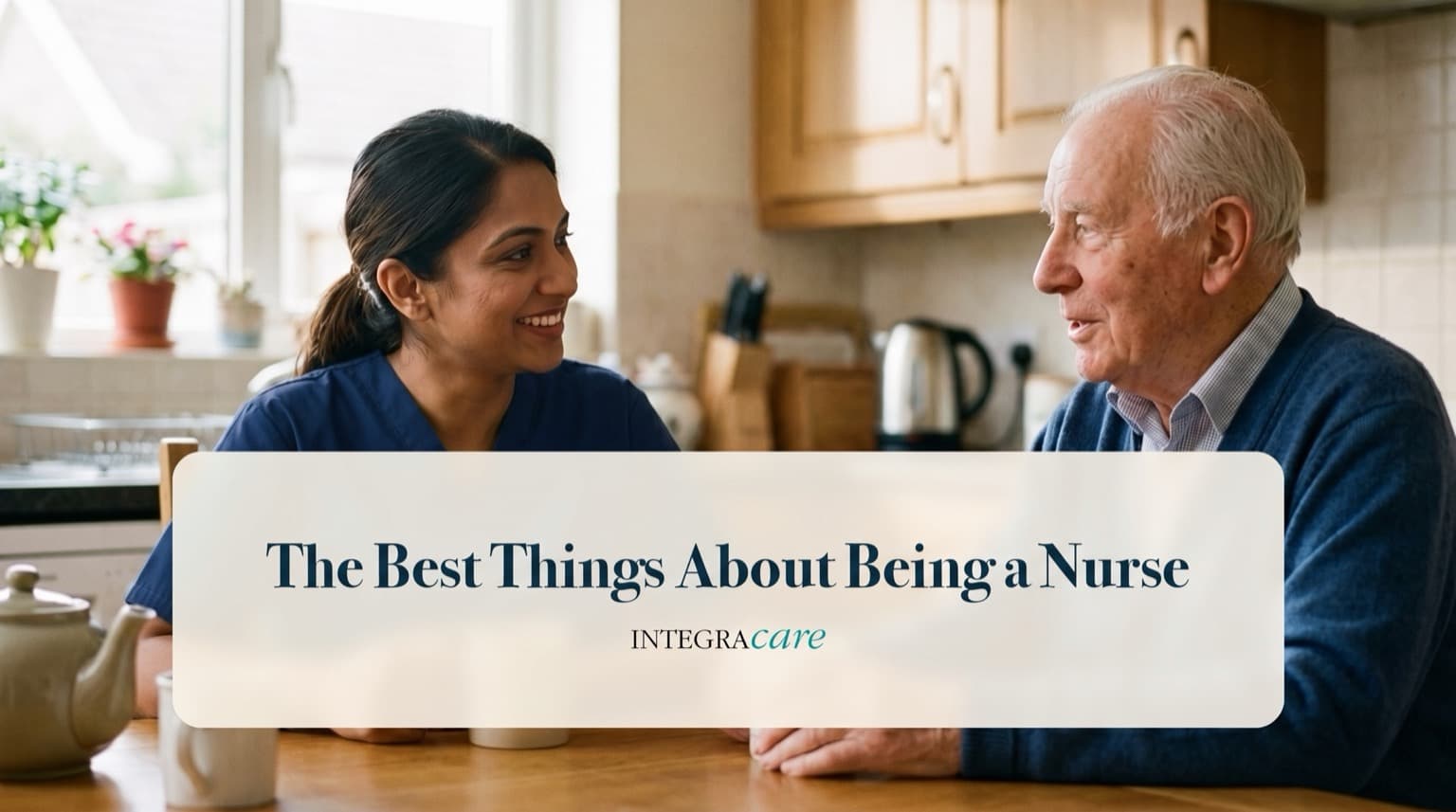 A home care nurse in navy scrubs and a senior man smile at each other over tea at his kitchen table