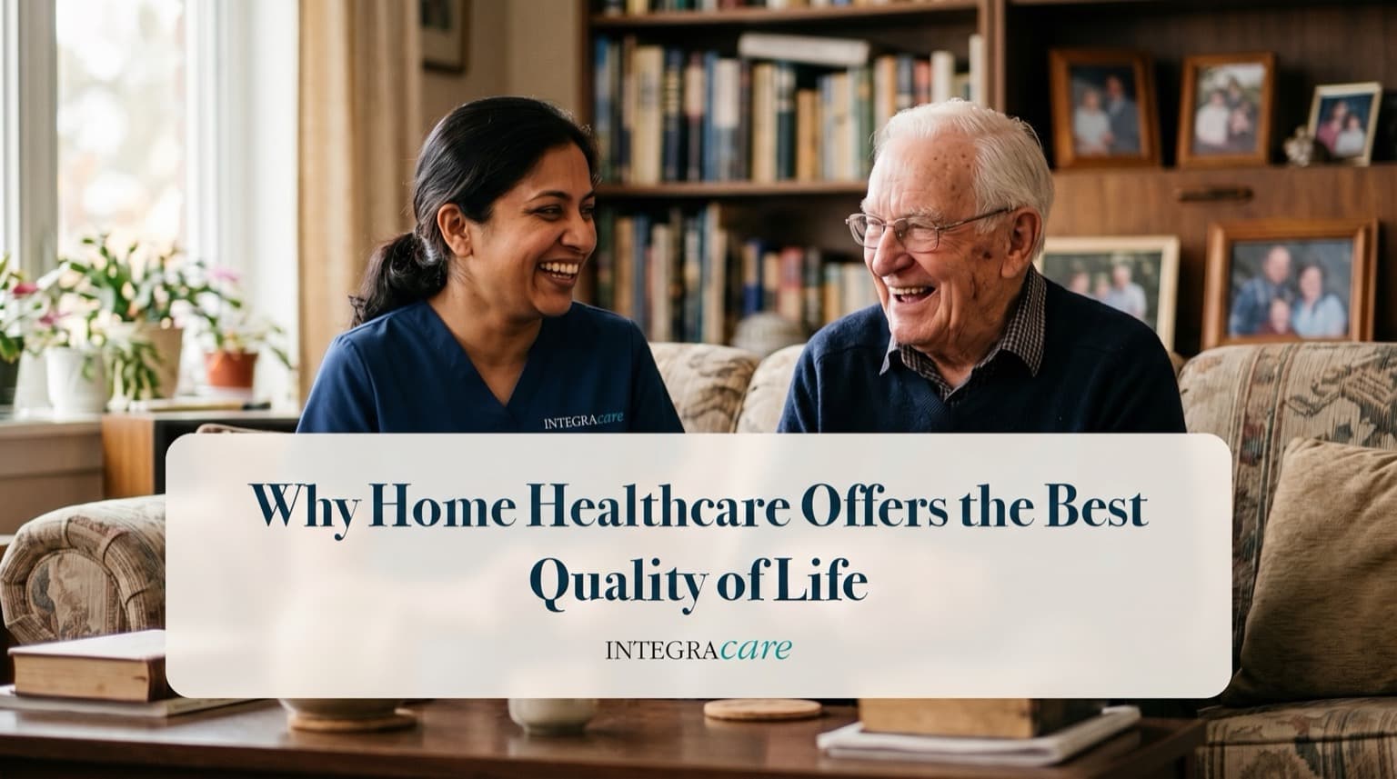 Caregiver and an older man laughing together on a couch in a living room filled with books and family photos