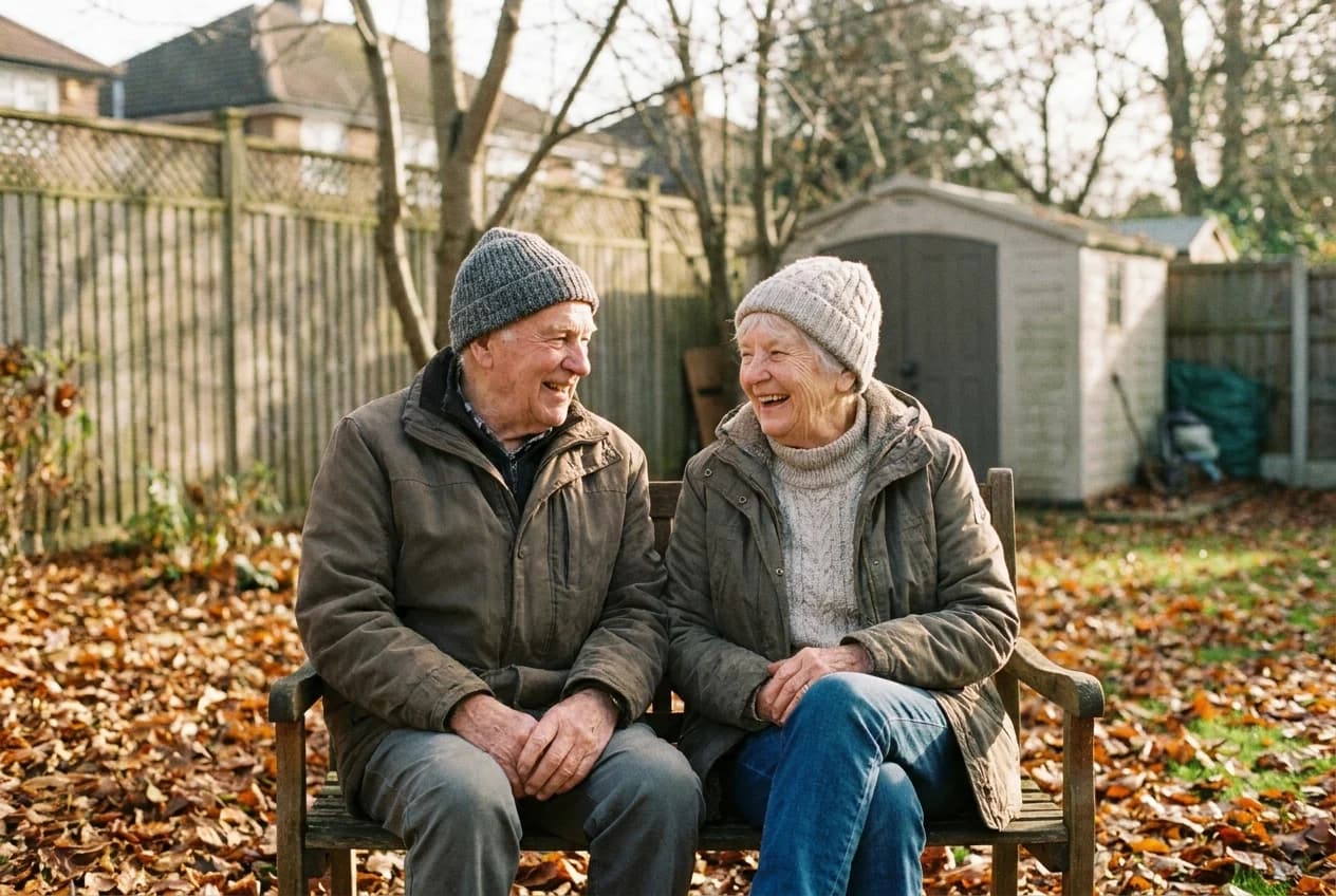 An older couple laughing together on a garden bench