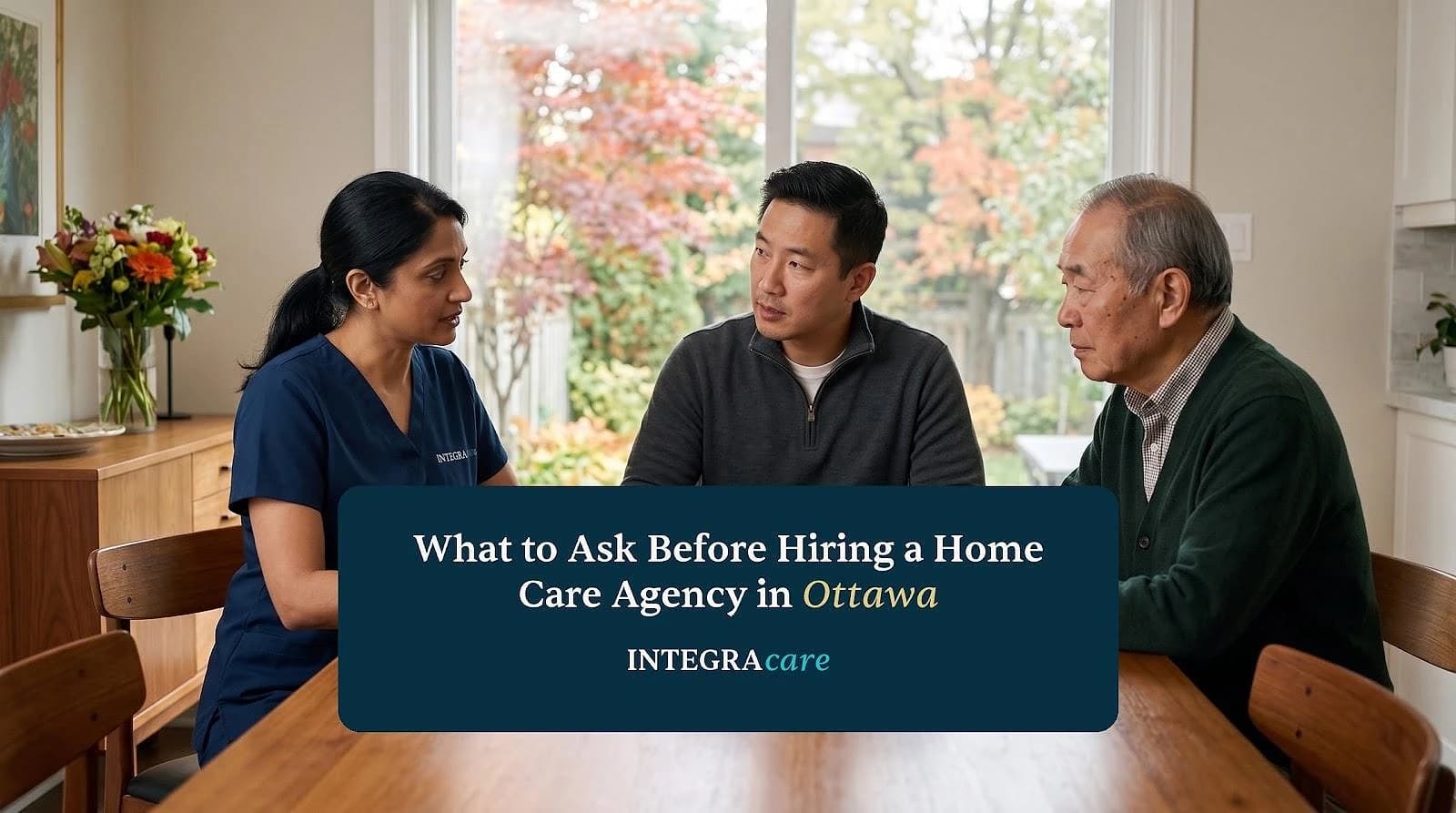 An adult son and his father sit at the kitchen table with a nurse, asking questions and taking notes.