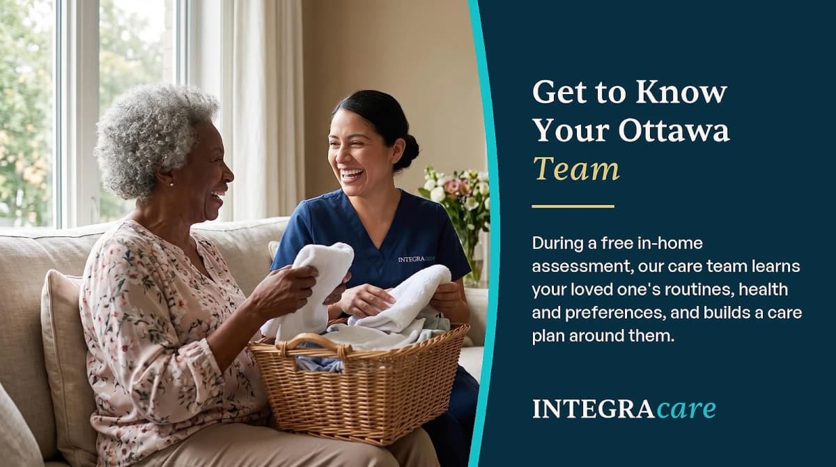 A Caregiver and an older woman laugh together while folding laundry in a bright living room.