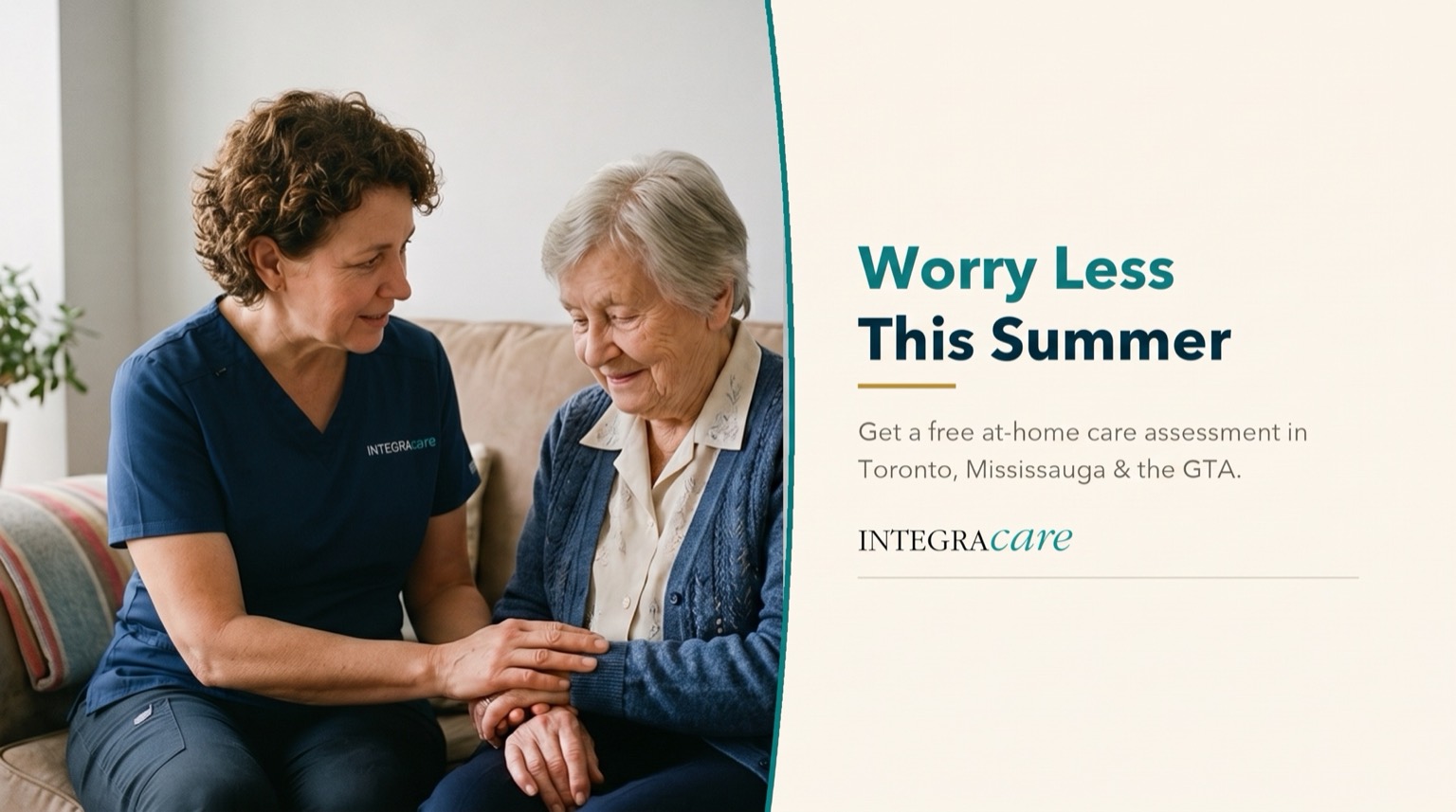 A caregiver in navy scrubs holding the hands of a smiling senior woman in a cardigan as they sit together on a couch