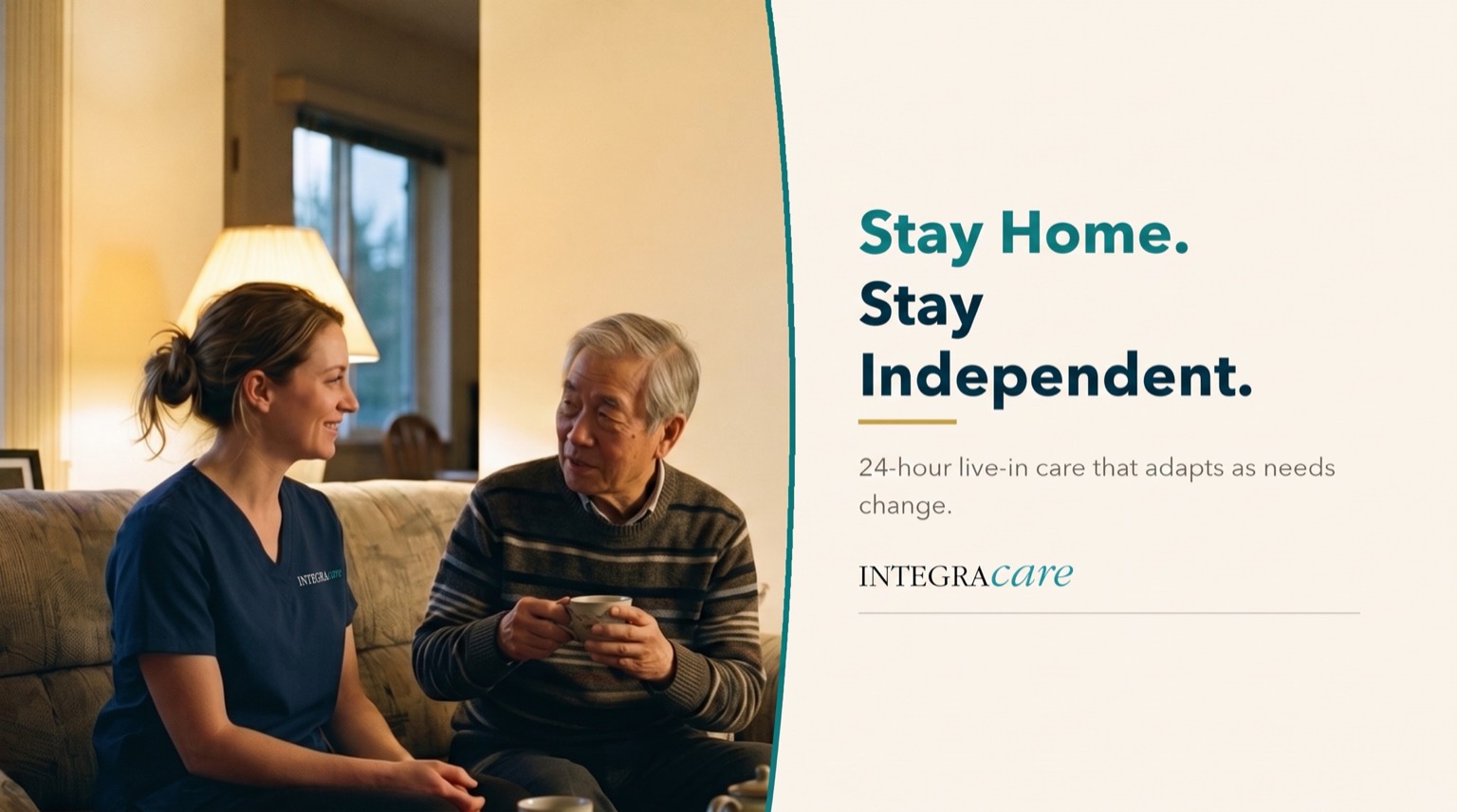 Caregiver in navy scrubs chatting with a senior man holding a mug on his living room sofa