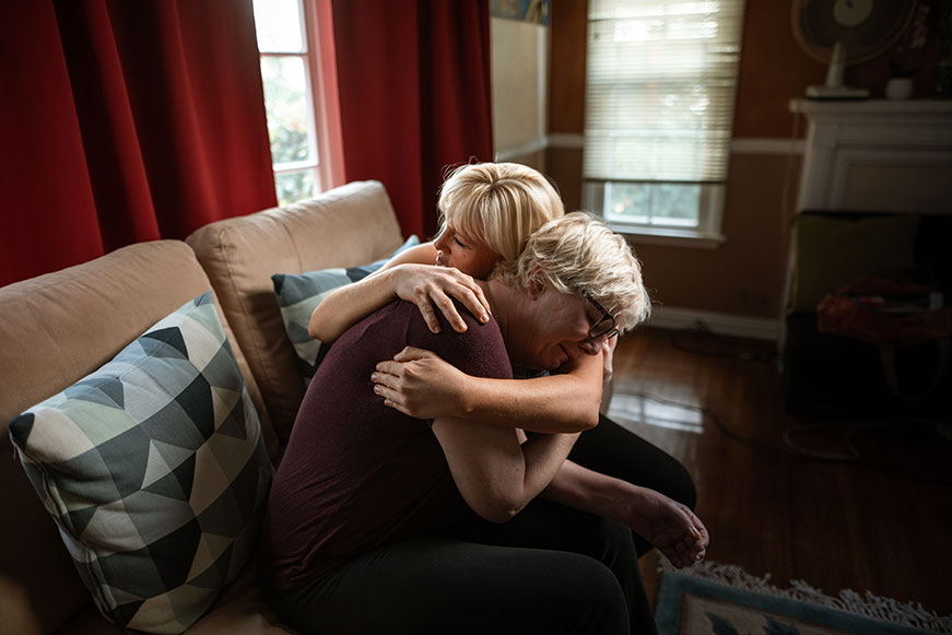 Two women embracing on a sofa at home