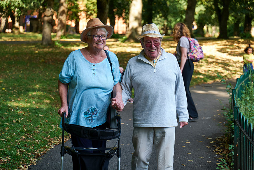 Senior woman using a mobility device while walking hand-in-hand with a Senior man