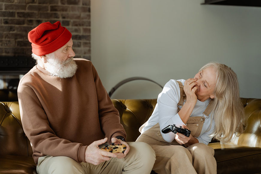 Senior couple sitting on a couch playing video games