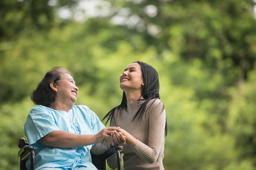 Picture of caregiver holding hand of senior in wheelchair