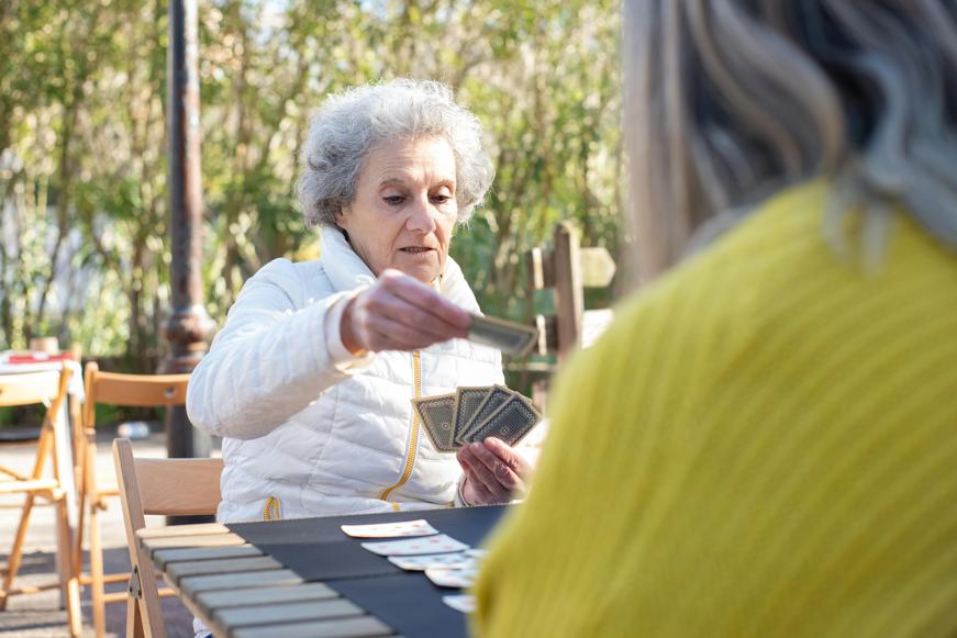 Elder lady playing cards outside with another person