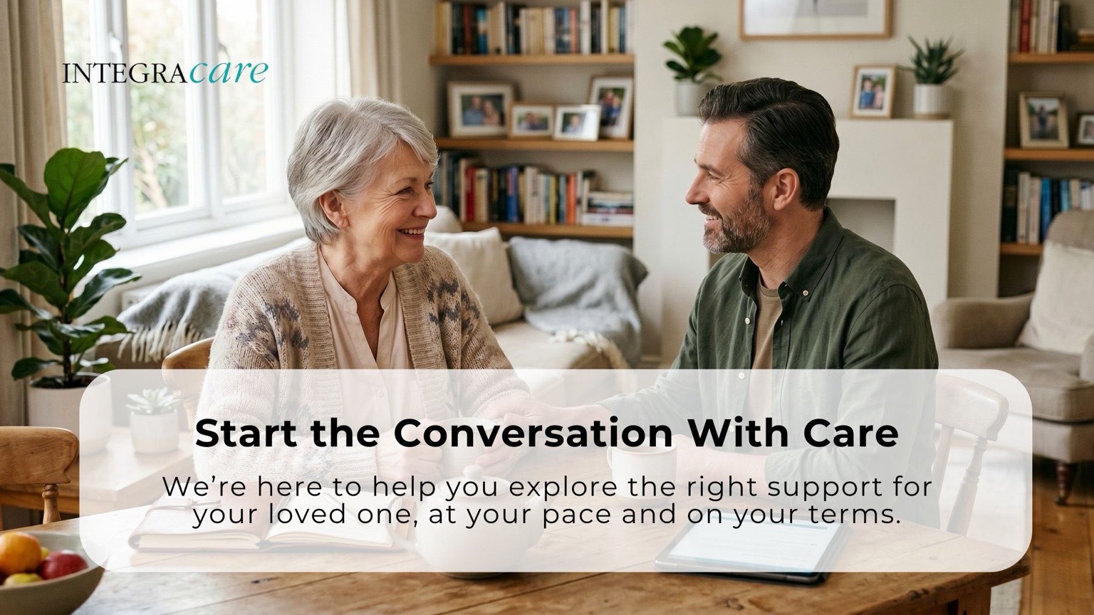 Senior woman smiling while speaking with an adult family member at a table, representing starting the conversation about personalized home care support and guidance for aging loved ones.